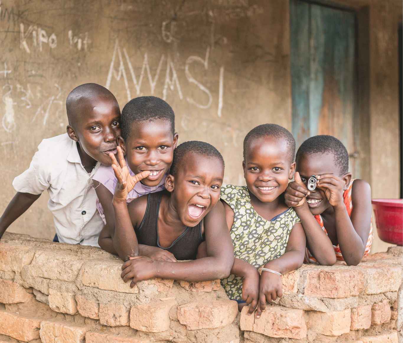 Five boys sit atop a brick wall in Tanzania.