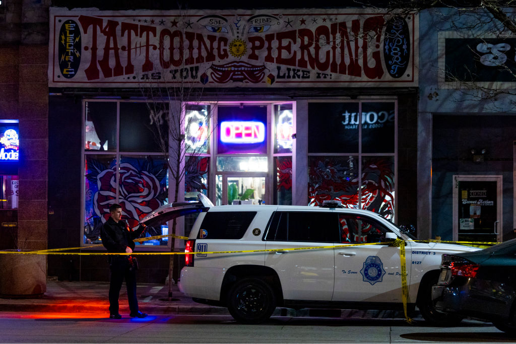 Police officers stand outside Sol Tribe tattoo shop on Broadway where two women were killed and a man was injured in a shooting.